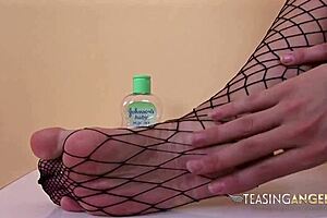 A curvy brunette with massive breasts goes down on herself with a big dildo in fishnet leggings while doing a foot job