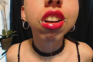 A petite and pretty goth teenage girl puts on hot pink lipstick and drools.
