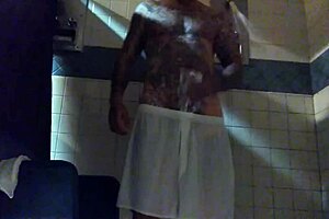 This is a tattooed white man with a large penis and he is masturbating in the shower
